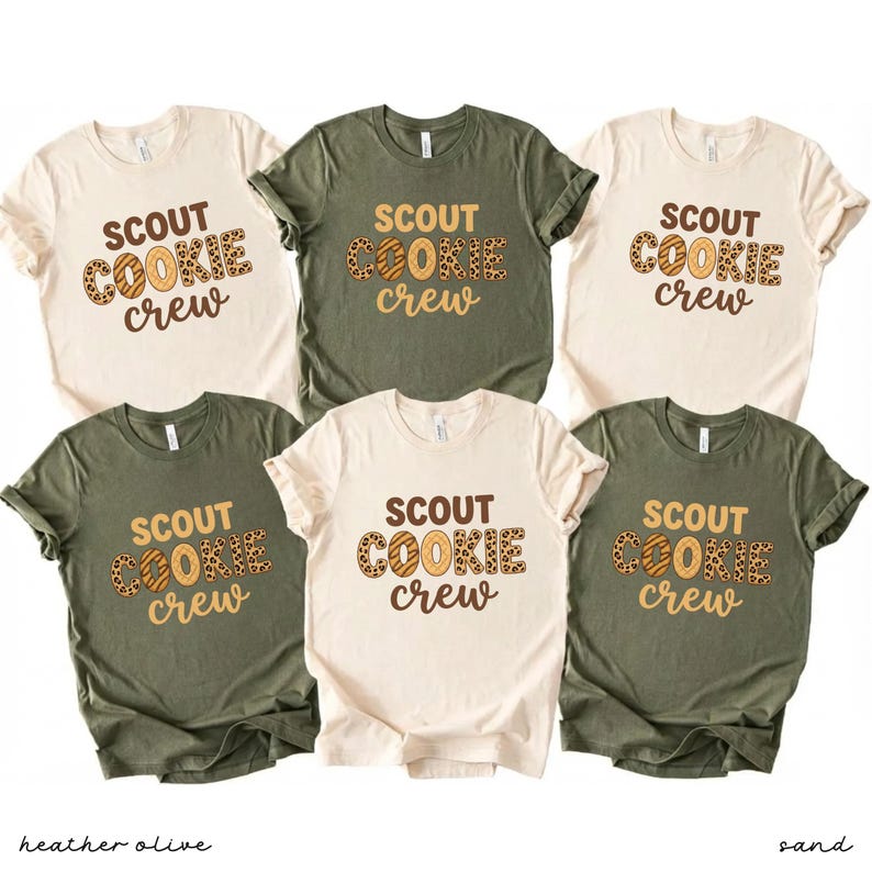 May include: Six short-sleeved t-shirts in sand and heather olive colors. Each shirt features the text "SCOUT COOKIE crew" in a brown and tan design. The shirts are displayed on a white background.