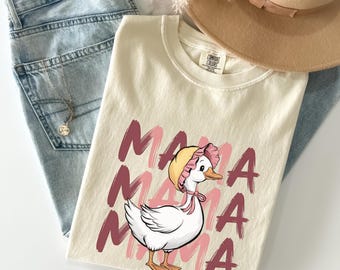 May include: Ivory t-shirt with a pink and white duck wearing a pink bonnet and the word "Mama" repeated four times in pink.