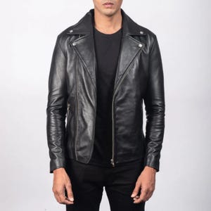 May include: A black leather jacket in a biker style. It has a notched collar, an asymmetrical zip, and zipped pockets. The sleeves are long and fitted. The jacket is likely made of good quality leather, and is a classic design.