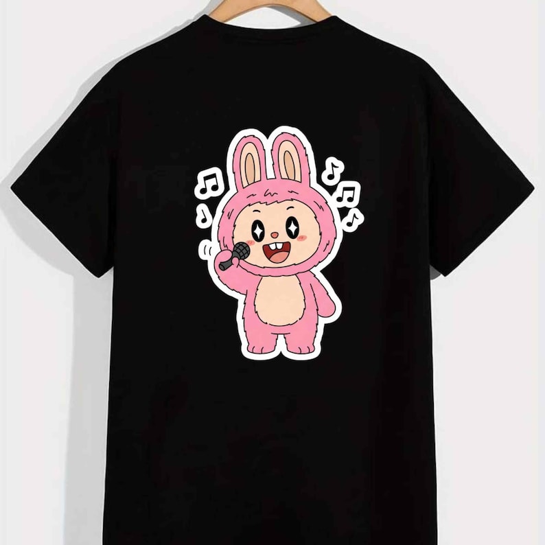 May include: Black t-shirt featuring a cartoon bunny character in a pink costume holding a microphone. The bunny is singing, with musical notes around it. The design is a fun and playful graphic.