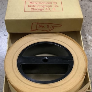 May include: A beige paper tape roll for a Continental No. 5 Instructograph machine, housed in a tan cardboard box. The box lid features red text reading CONTINENTAL, No. 5, and Manufactured by Instructograph Co. Chicago 40, Ill.