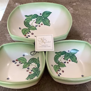 May include: Three square ceramic bowls with rounded corners, featuring a light green gradient rim and a central botanical illustration of blackberry vines with green leaves and dark berries. A white tag reads Kate Kessler Botanical Art on Royal Haeger Artware.