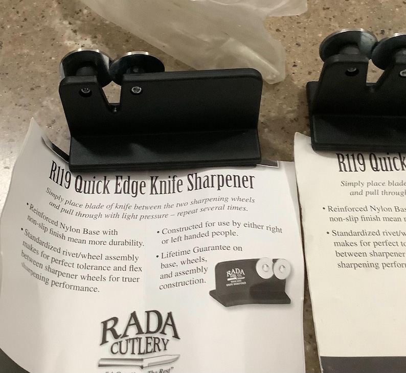 May include: Black R119 Quick Edge Knife Sharpener with two sharpening wheels. The product features a reinforced nylon base and a standardized rivet/wheel assembly. The packaging includes the RADA CUTLERY logo and product information.