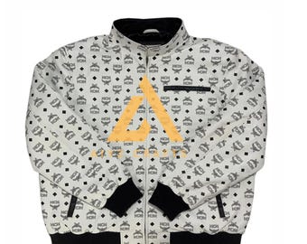 Puede incluir: Chaqueta bomber blanca con un patrón de monograma blanco y negro. La chaqueta tiene una cremallera y puños y cintura de canalé negros.