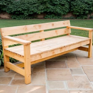 May include: A wooden bench with a natural finish and a slatted back. The bench has two armrests and is made of solid wood.