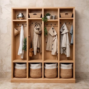 Puede incluir: Un organizador de entrada de madera con múltiples compartimentos. Cuenta con ganchos para colgar, cestas tejidas y estantes con objetos decorativos y abrigos. El acabado de madera natural y los tonos neutros crean una estética cálida y acogedora.