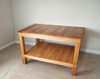 May include: A wooden table with a shelf. The table is made of light brown wood and has a simple design.