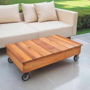 Può includere: Un tavolino da caffè in legno con finitura in legno naturale e quattro ruote. Il tavolo è realizzato con assi di legno e ha una forma rettangolare.