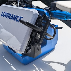May include: A blue and white Lowrance fish finder with black and blue components. The device is designed for marine use and features a screen with the brand name prominently displayed. The unit is mounted on a blue base.