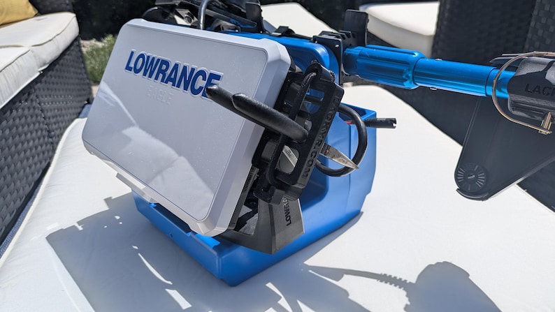 May include: A blue and white Lowrance fish finder with black and blue components. The device is designed for marine use and features a screen with the brand name prominently displayed. The unit is mounted on a blue base.
