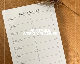 May include: A white printable weekly planner with the text "WEEKLY PLANNER" and "PRINTABLE WEEKLY PLANNER". The days of the week are listed, with space for notes. The planner is on a wooden surface.