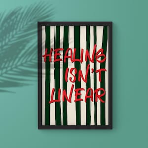 以下が含まれることがあります： 「HEALING ISN'T LINEAR」の赤い手書き風の文字が書かれた額入りのアートプリント。背景には緑と白の縦縞模様があります。フレームは黒で、プリントはヤシの葉の影のあるティール色の壁に表示されています。