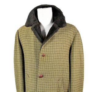May include: A vintage tweed coat with a dark brown faux fur collar. The coat features a classic plaid pattern in shades of olive green and brown, with two brown buttons. The coat is displayed on a mannequin.