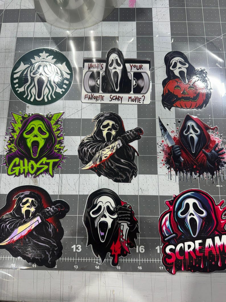 May include: A collection of nine vinyl stickers featuring the Ghostface character from the Scream franchise. Designs include a coffee-inspired logo, a VHS tape with the text "What's Your Favorite Scary Movie?", and various illustrations of the masked figure holding knives, pumpkins, or surrounded by colorful graphic elements and the word "Scream".