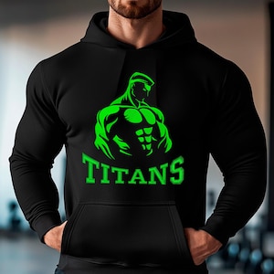 Peut inclure: Sweat à capuche noir avec un motif vert d'une silhouette musclée et le mot "TITANS" en vert. Le sweat-shirt est doté d'une poche avant et d'une capuche à cordon.