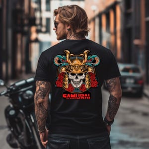 Op de afbeelding: Zwart t-shirt met een gedetailleerde afbeelding van een samoerai-schedel met een gouden helm, rode rozen en groene slangen. Het woord "SAMURAI" staat in het rood onderaan het ontwerp. Het t-shirt wordt door een persoon gedragen.