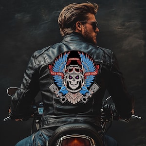 Peut inclure: Veste en cuir noir avec un grand écusson circulaire représentant un crâne portant un casque et des lunettes, avec des ailes bleues et les mots "LIVE FREE RIDE FREE" en rouge. La veste est portée par une personne sur une moto.