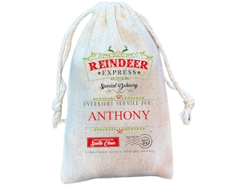 May include: A beige burlap drawstring bag with the text "REINDEER EXPRESS" in red and green. The bag reads "OVERNIGHT SERVICE FOR ANTHONY" in red. The bag also has a "CHECKED TWICE BY SANTA CLAUS" stamp.