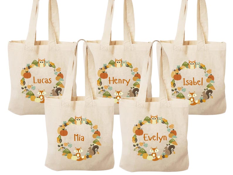 May include: Five beige canvas tote bags with brown handles. Each bag features a circular design with a brown squirrel, a brown owl, and a brown fox. The bags are personalized with the names Lucas, Henry, Isabel, Mia, and Evelyn.