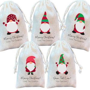 May include: Five white fabric gift bags with red and green gnome designs. The bags have drawstrings and are decorated with the text "Merry Christmas!" and "Love, The Guarinos". One bag has the text "Your Text Line 1" and "Your Text Line 2".