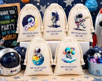 Puede incluir: Cinco bolsas de algodón de color crema con cordón, decoradas con ilustraciones coloridas de astronautas y el texto impreso "HOPE YOU HAD A BLAST! LOVE, LIAM". Cada bolsa muestra un gráfico espacial único, incluyendo astronautas en planetas, nubes o tocando la guitarra.