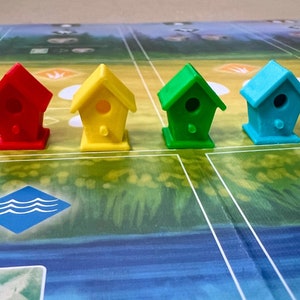 May include: Five colourful birdhouses in a row on a game board. The birdhouses are red, yellow, green, blue and purple.