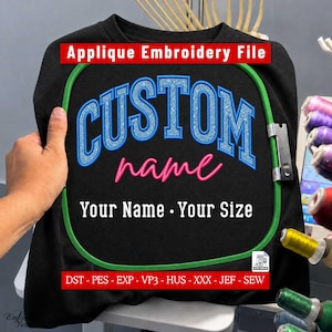 Könnte beinhalten: Ein schwarzes Stoffstück in einem grünen Stickrahmen mit dem Text Applique Embroidery File oben. Das Design zeigt das Wort CUSTOM in blauem Glitzer, das Wort name in pinker Schreibschrift und Your Name Your Size darunter.