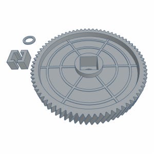 Puede incluir: Un engranaje gris con un orificio central cuadrado, rodeado de líneas radiales y dientes. También hay un pequeño anillo gris y un bloque gris con un recorte en forma de U. Los objetos parecen estar impresos en 3D.