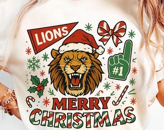 Könnte beinhalten: Cremefarbenes T-Shirt mit festlichem Weihnachtsdesign. Die Grafik zeigt einen brüllenden Löwen mit Weihnachtsmütze, umgeben von Schneeflocken, Zuckerstangen und den Worten "Merry Christmas". Ein grüner Fächer-Schaumstofffinger zeigt die Nummer "#1".