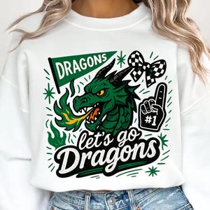 May include: White sweatshirt featuring a green dragon graphic with the text "Dragons" on a banner and "Let's go Dragons" in a stylized font. Includes a #1 foam finger and a checkered bow.