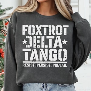 May include: A dark gray sweatshirt with the text "FOXTROT DELTA TANGO" in white, with the words "RESIST. PERSIST. PREVAIL." below.