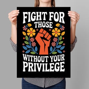 May include: Black poster with the text "FIGHT FOR THOSE WITHOUT YOUR PRIVILEGE" in white, stylized font. An orange fist is centered, surrounded by colorful flowers and leaves.