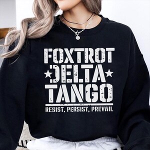 May include: Black sweatshirt with white text that reads "FOXTROT DELTA TANGO" and "RESIST. PERSIST. PREVAIL."