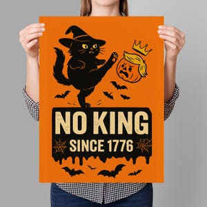 May include: Orange poster with a black cat kicking a pumpkin wearing a crown. The poster has the text "NO KING SINCE 1776" with bats and spiderwebs. A Halloween-themed design.
