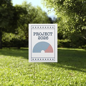 May include: A white yard sign with the text "PROJECT 2026" and a graphic of a half-circle divided into blue and red dots. The sign is held up by a metal stake and placed on a grassy lawn.
