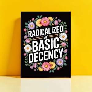 May include: Black rectangular art print featuring the text "RADICALIZED BY BASIC DECENCY" in white, encircled by a floral wreath of pink, yellow, purple, and white flowers. The background is a solid yellow.