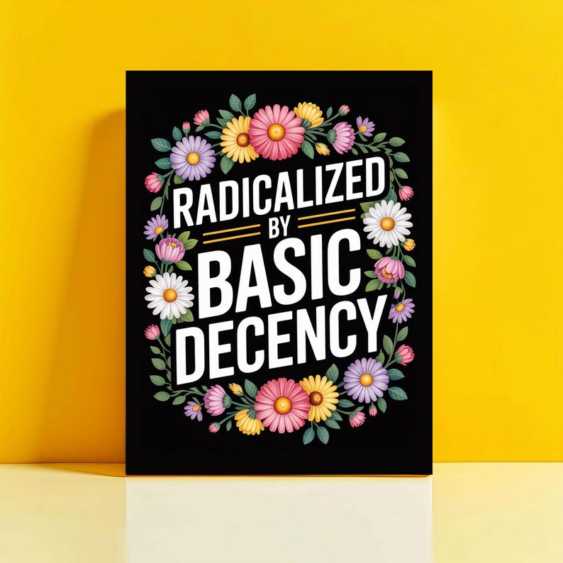 May include: Black rectangular art print featuring the text "RADICALIZED BY BASIC DECENCY" in white, encircled by a floral wreath of pink, yellow, purple, and white flowers. The background is a solid yellow.