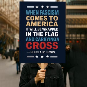 Könnte beinhalten: Ein Schild mit dem Zitat von Sinclair Lewis: „Wenn der Faschismus nach Amerika kommt, wird er in die Flagge gehüllt sein und ein Kreuz tragen.“ Der Text ist weiß, gold und rot auf marineblauem Hintergrund.