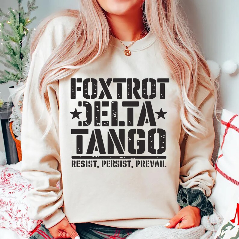 May include: A cream-colored sweatshirt with black text that reads "FOXTROT DELTA TANGO" and "RESIST, PERSIST, PREVAIL."