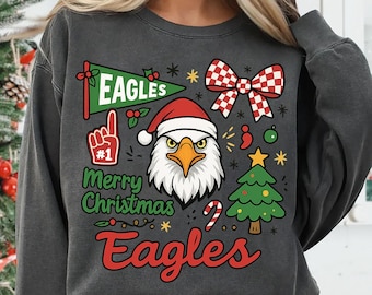 May include: Dark gray sweatshirt with a festive design. Features a cartoon eagle wearing a Santa hat, a green pennant that says "Eagles", and the words "Merry Christmas Eagles" in red and green.