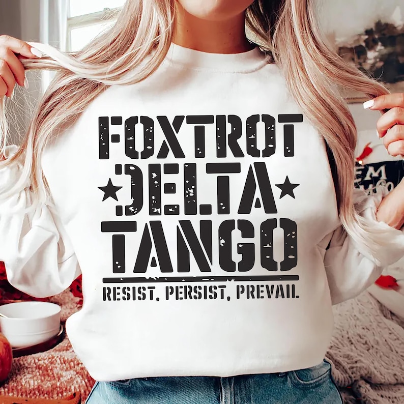 May include: White sweatshirt with black text that reads "FOXTROT DELTA TANGO RESIST, PERSIST, PREVAIL."