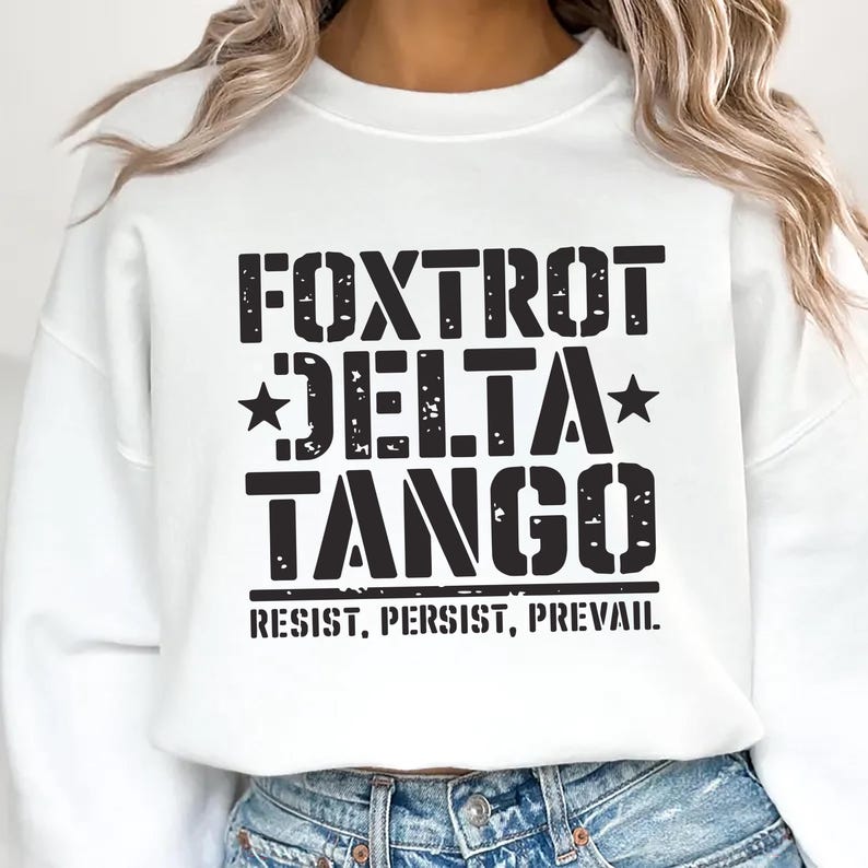 May include: White sweatshirt with black text that reads "FOXTROT DELTA TANGO RESIST. PERSIST. PREVAIL."