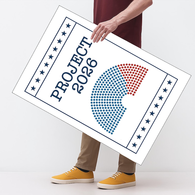 May include: A white sign with the text "PROJECT 2026" in navy blue, featuring a graphic of blue and red dots. The sign is held by a person wearing a maroon shirt, khaki pants, and yellow sneakers.