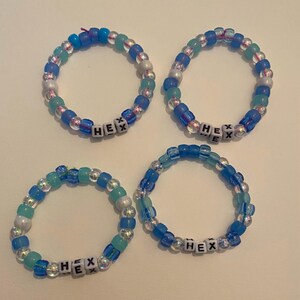 May include: Four blue and white beaded bracelets with the word "HEX" spelled out in black letters on each bracelet.