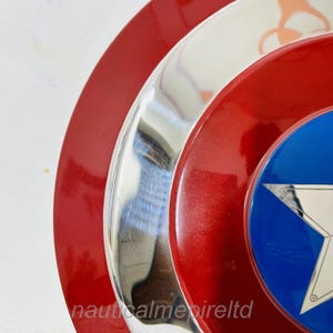 May include: A red, white and blue Captain America shield with a silver metal centre. The shield has a star in the centre.