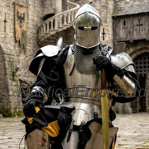 May include: A suit of polished steel plate armor featuring a closed helmet, chainmail neck protection, shoulder pauldrons, and gauntlets. The armor includes a breastplate and leg greaves, worn over black and yellow clothing, holding a long sword.