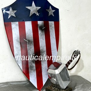 May include: A red, white, and blue shield with five white stars, a distressed look, and a silver hammer with a brown leather handle.