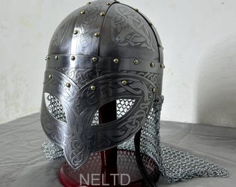 May include: A silver Viking helmet with intricate knotwork designs and a chainmail aventail. The helmet is on a wooden stand and has a brass finish.