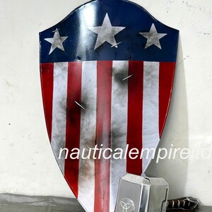 May include: A red, white, and blue shield with a star design, similar to the American flag, with a silver metal hammer with a black handle and a three-pointed star design on the head.
