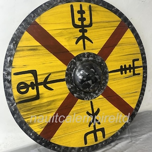 May include: A round wooden shield with a yellow background and red stripes. The shield has a black metal rim with studs and a black metal boss in the center. The shield is decorated with black Viking runes.